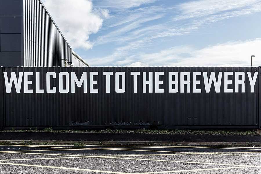 A wall with the words Welcome to the Brewery written across it in white text.