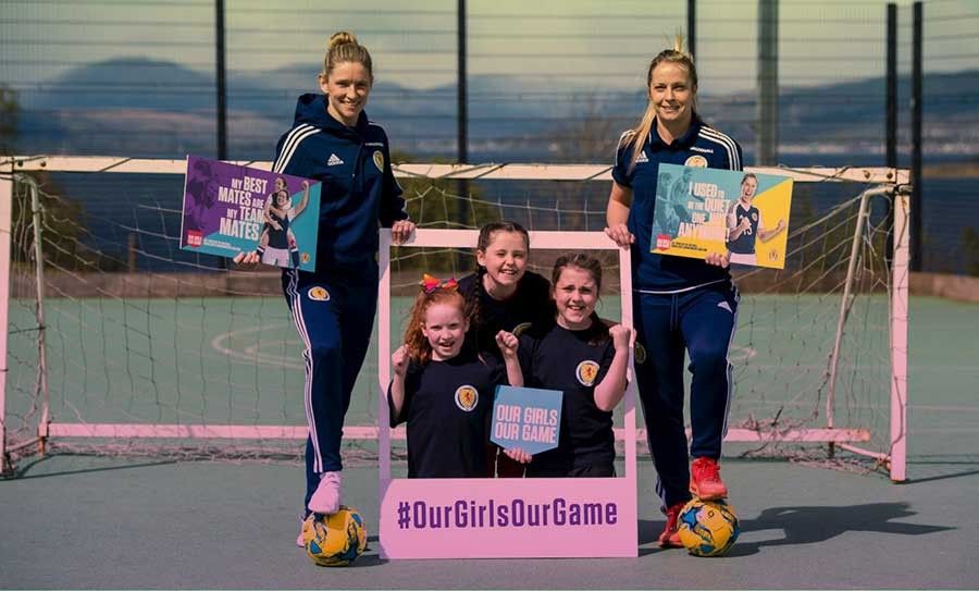 Two female footballers pose for a photo with school children to promote UEFA's football campaign.